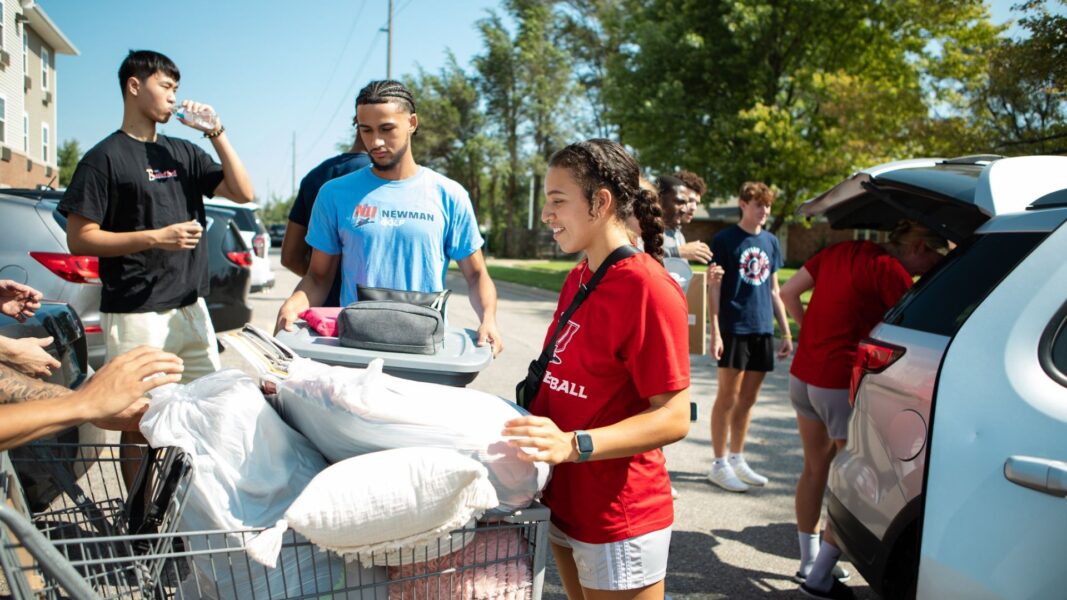 Volunteers help unload a car during new student move-in day.