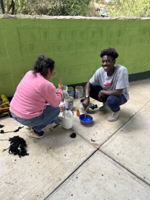 (Right) Newman student Ezekiel Kemboi uses paint to bring new life to a recreational area during a service opportunity.