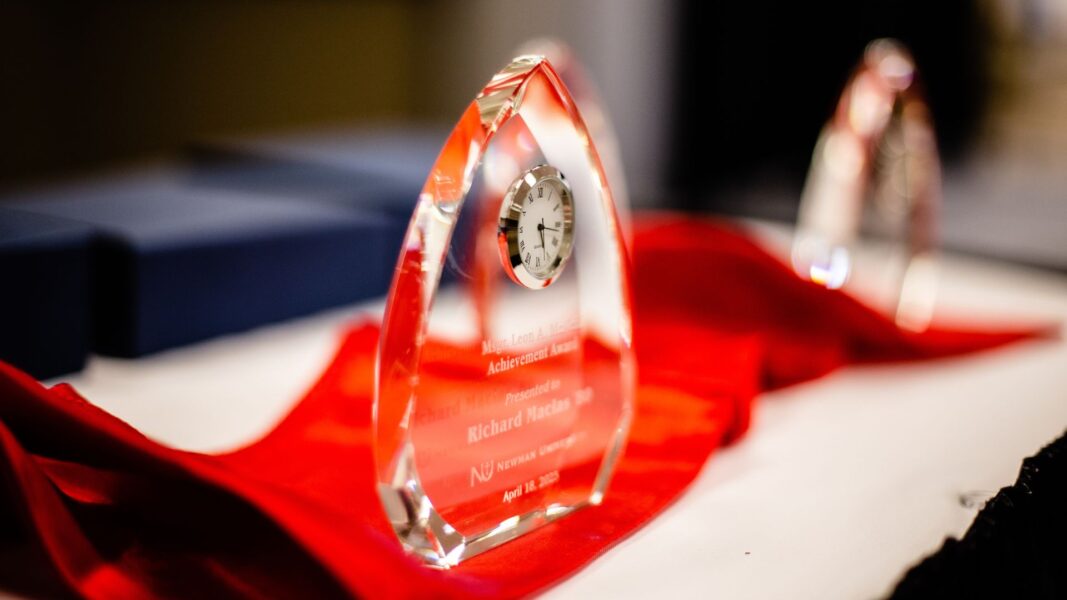 A clear, crystal award with a clock sits upon a red cloth at the banquet.