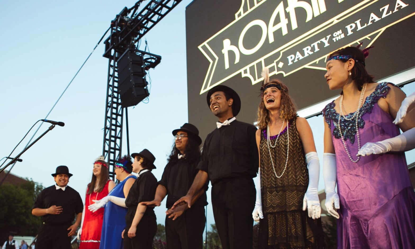 The Newman troubadours perform in flapper dresses and caps during the roaring 20's themed Party on the Plaza.