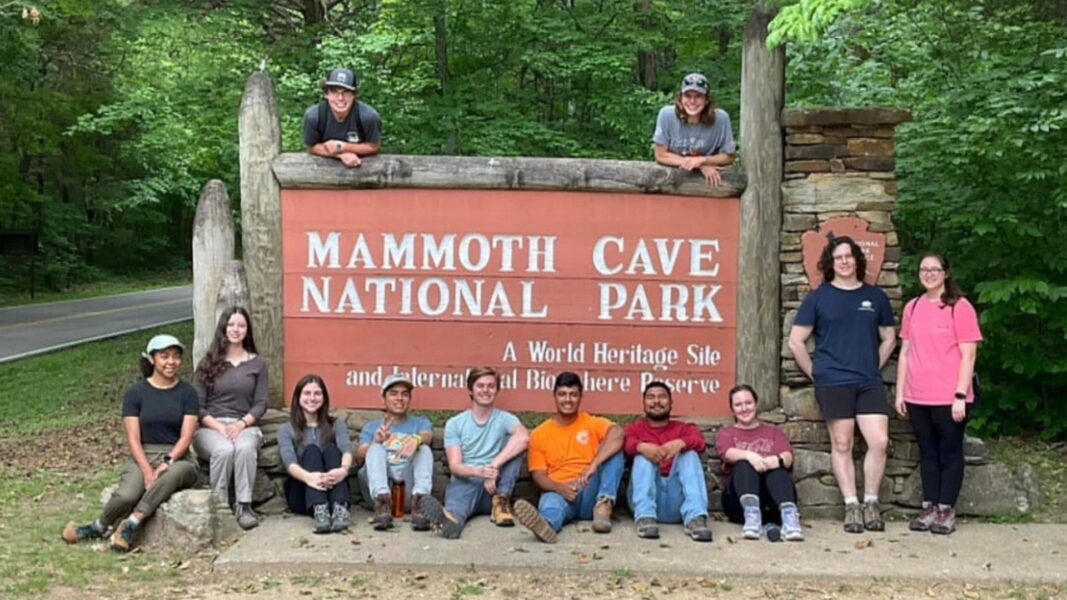 The group of NCHC students surrounds the "Mammoth Cave National Park" sign.