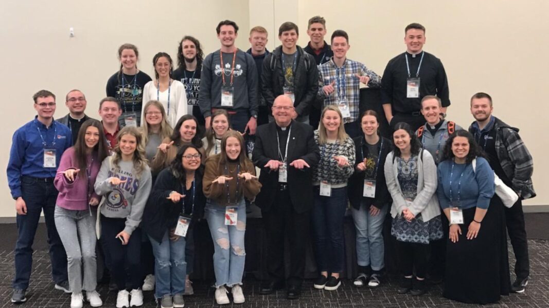 Students of Newman University and Wichita State University show off their Jet hands with the Most Rev. Bishop Carl A. Kemme.
