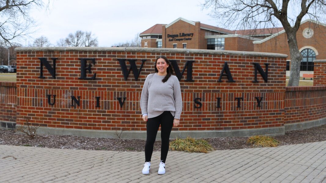 Turnquist in front of the Newman University sign on campus.