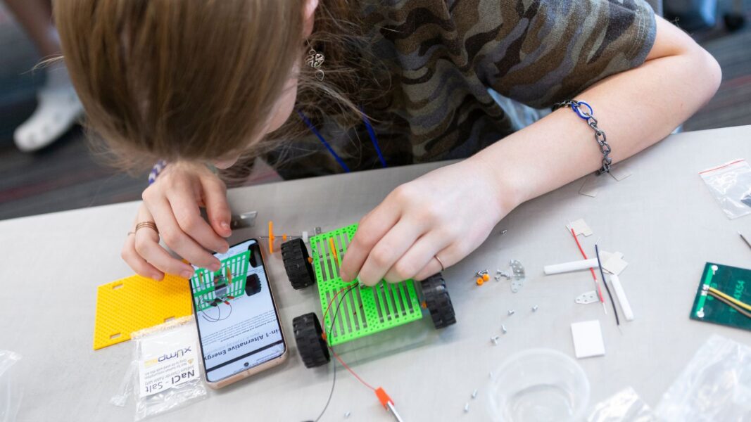 A student works on a model car using electrical energy.