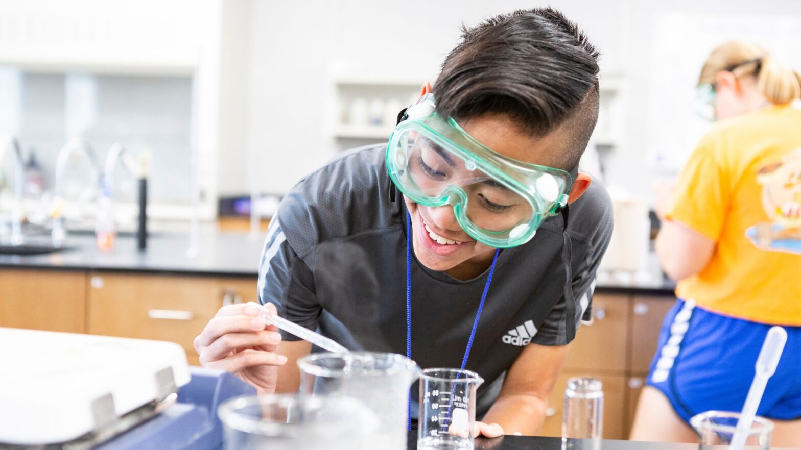 A student wearing goggles at the Investigative Summer STEM Program conducts an experiment.