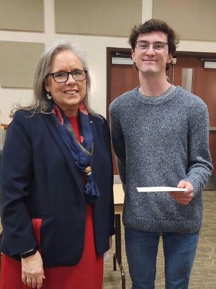 Newman President Kathleen Jagger congratulates freshman Matthew Fowler for his winning essay.