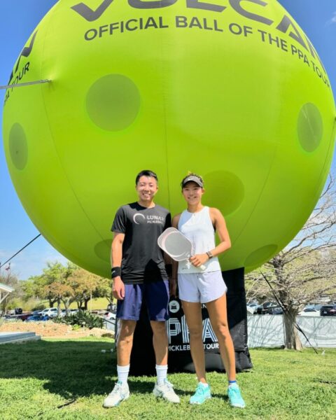 Kim and teammate in front of an inflatable pickleball at the PPA Tour.