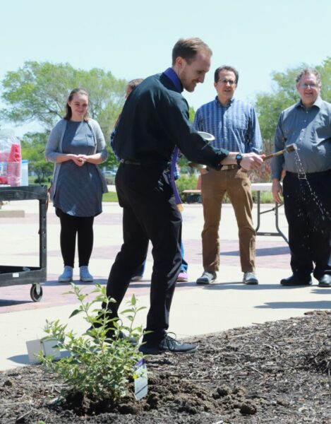 Father Adam Grelinger blesses the butterfly bushes with holy water.