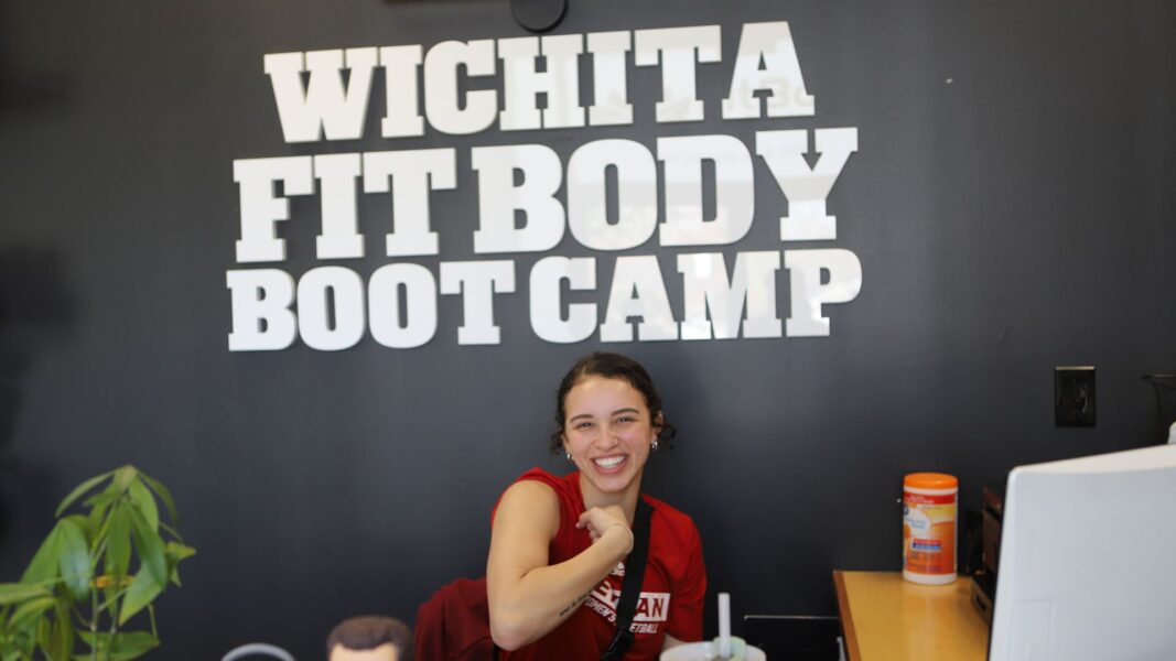 Amaya Perez flexing at the front desk of Fit Body Boot Camp.