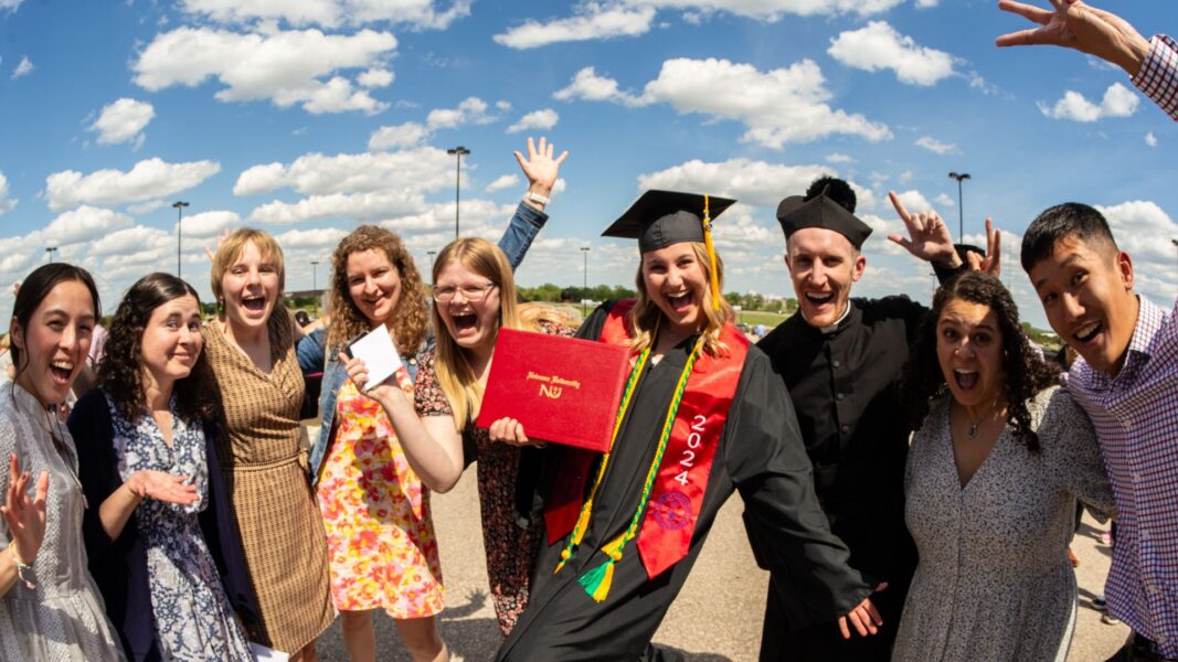 Helfrich, holding her diploma, celebrates with her Campus Ministry supporters outside Hartman Arena.