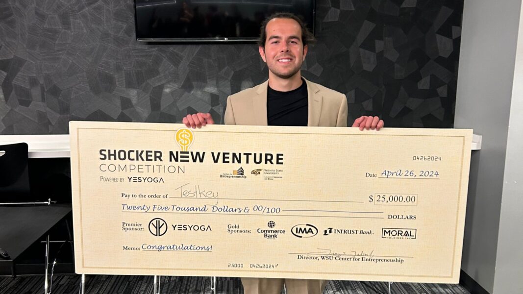 Nick Vasilescu holds up his first-place win of $25,000 in the form of a giant check.