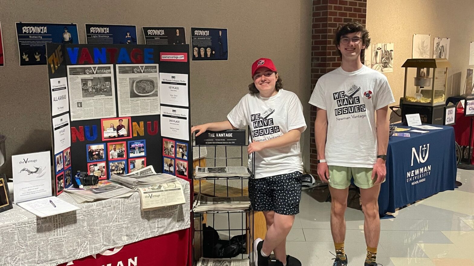 (From left to right) Victor Dixon and Matthew Fowler stand at a table with stories from The Vantage student newspaper.