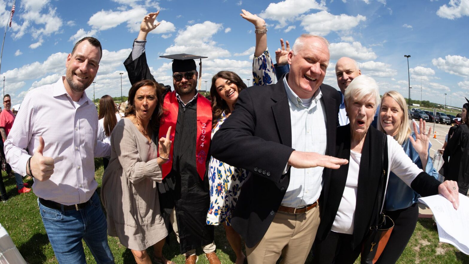 A graduate and his family celebrate outside Hartman Arena on Newman University commencement day.