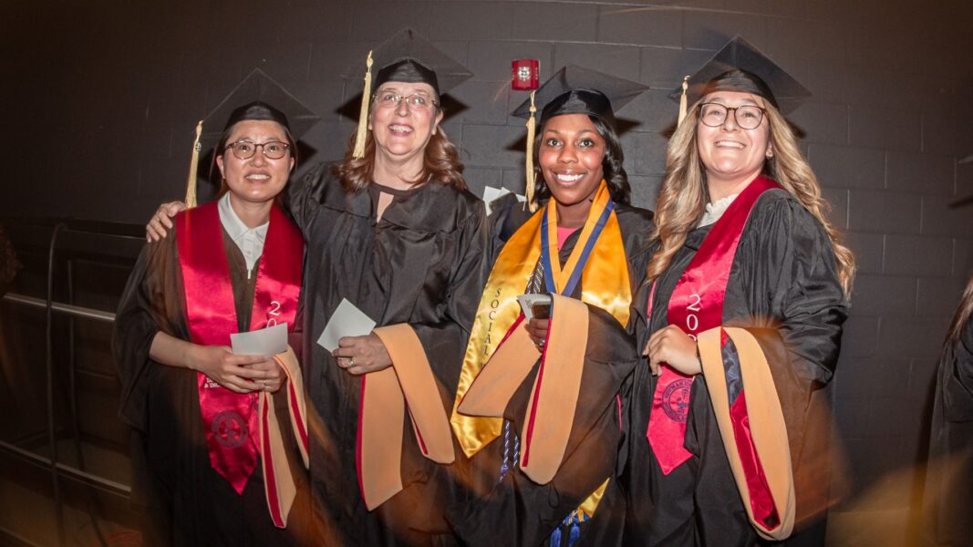 Kang (left) and fellow Newman University graduates