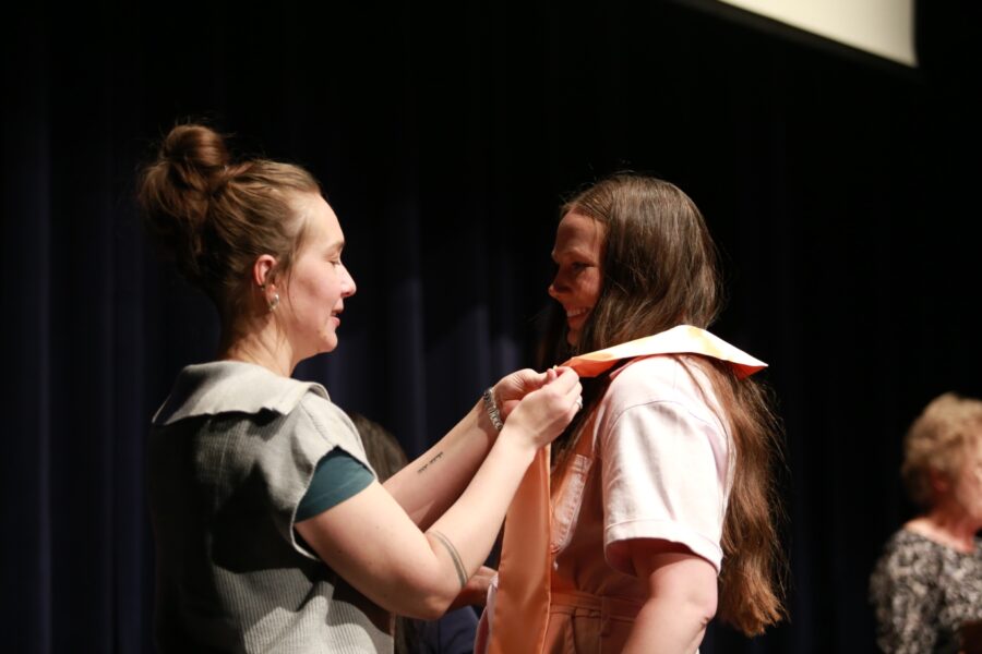 Newman nursing professor Rachel Cheek, APRN, CNM, gives Dopps her ceremonial nursing pin.