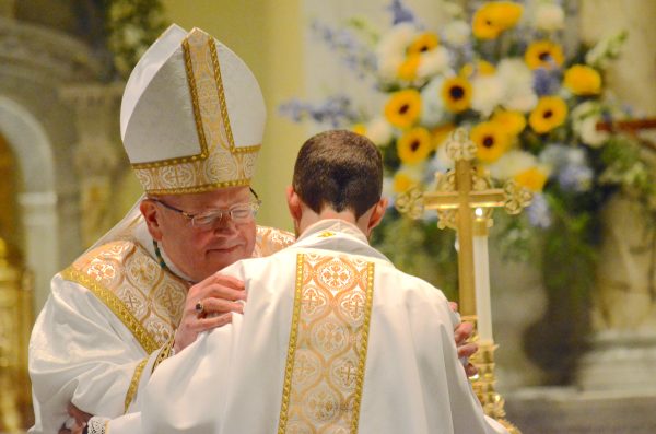 Bishop embraces Fr. Matthew Cooke after he received his priestly vestments. (Courtesy photo, Catholic Advance)