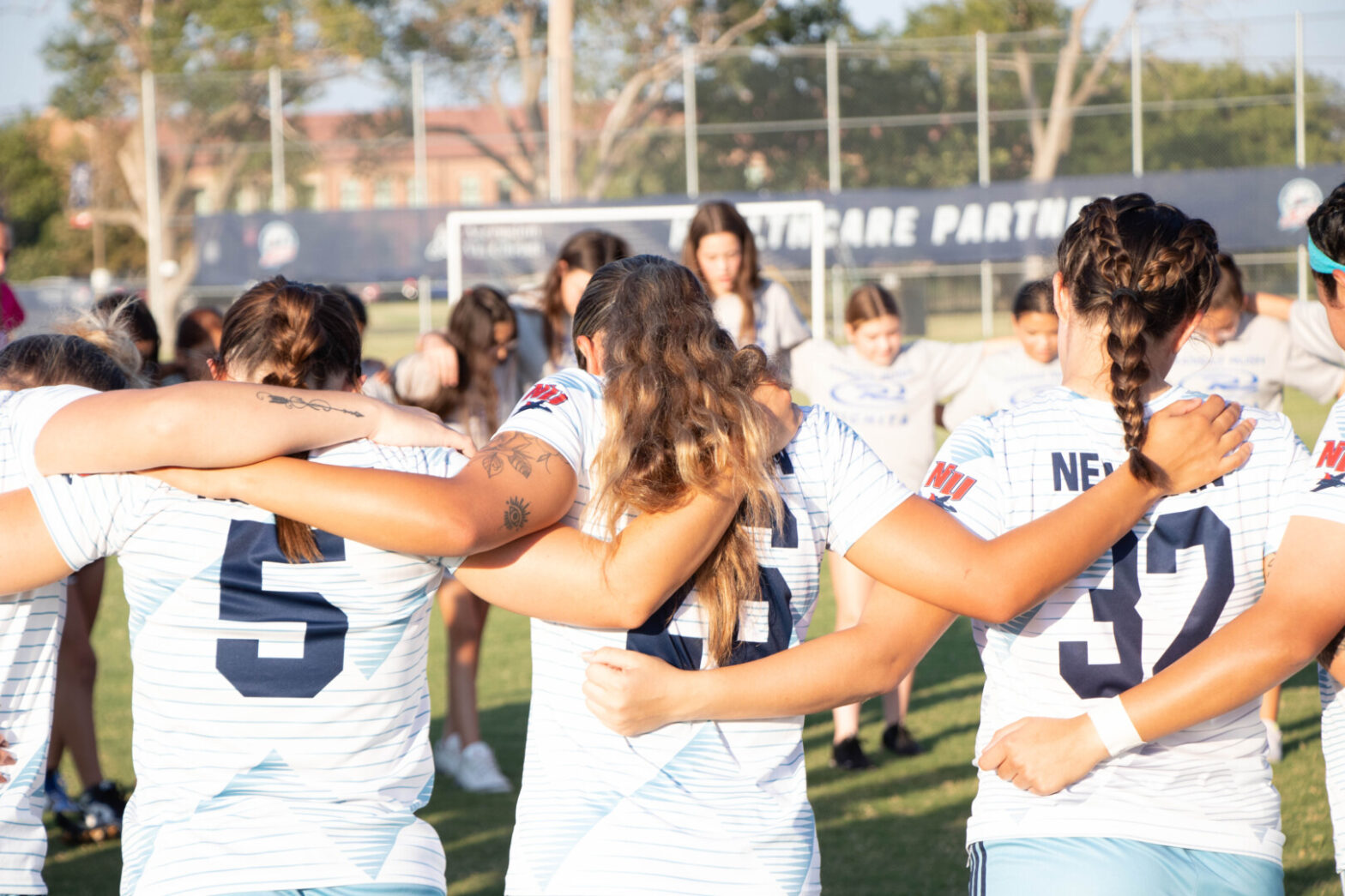 Newman University's women's soccer team embraces on the field.