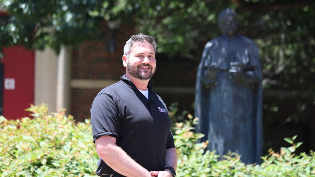 Ralls stands in front of the St. Newman sculpture outside of Sacred Heart Hall.