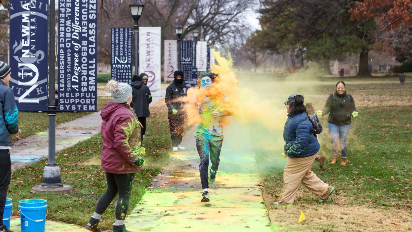 Students get splashed with colored powder as they run on Newman's campus during the Color Run.