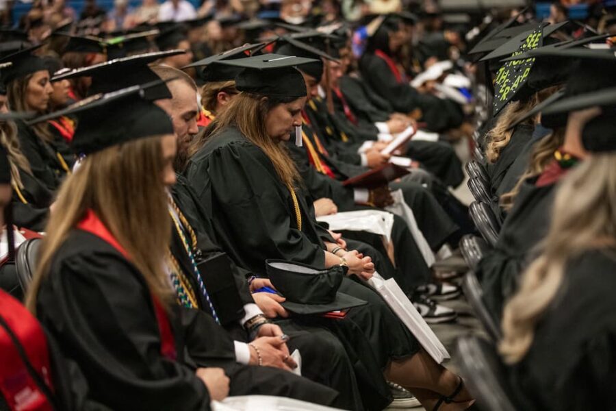 Woods bows her head in prayer at her graduation from Newman University in spring 2023.