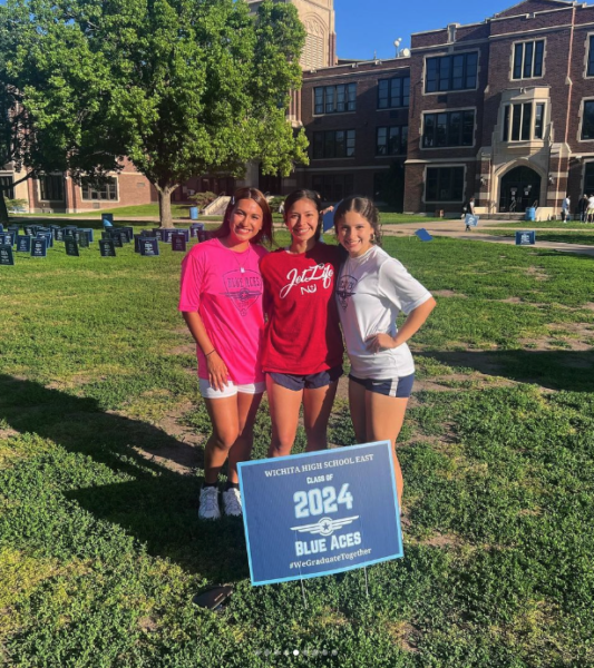 Cuellar (center) wears her Newman Jet shirt outside of East High School in Wichita.