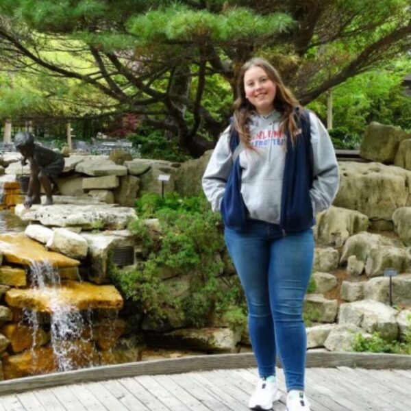 Kassidy Miller stands in front of a man made rock waterfall.