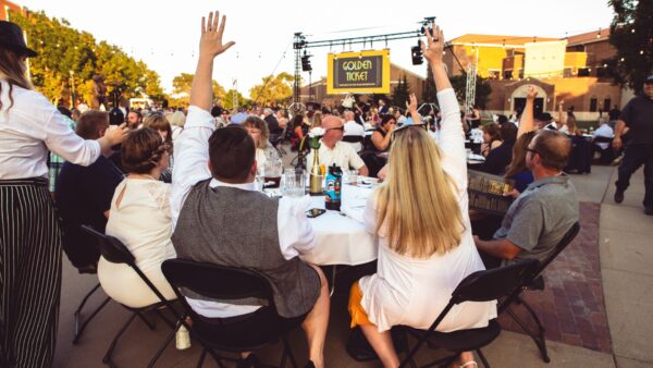 Two bidders excitedly raise their hands during the live auction portion of the Party on the Plaza fundraiser.