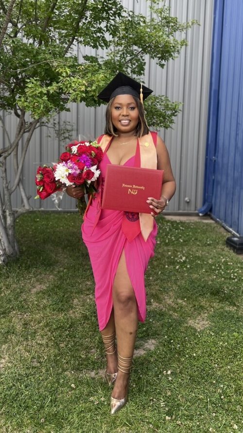 Kassita stands proudly with diploma in hand on Newman commencement day in May 2024.