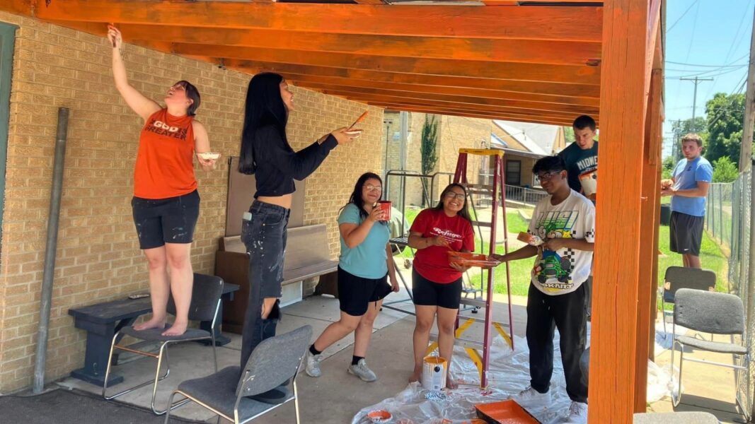 Arguijo (center, red shirt) helps stain wood with teen participants at Underground.