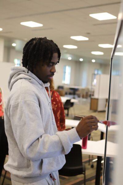 Student Eventz Malaska uses a bare paintbrush to paint digitally on the smart boards in the learning commons area.