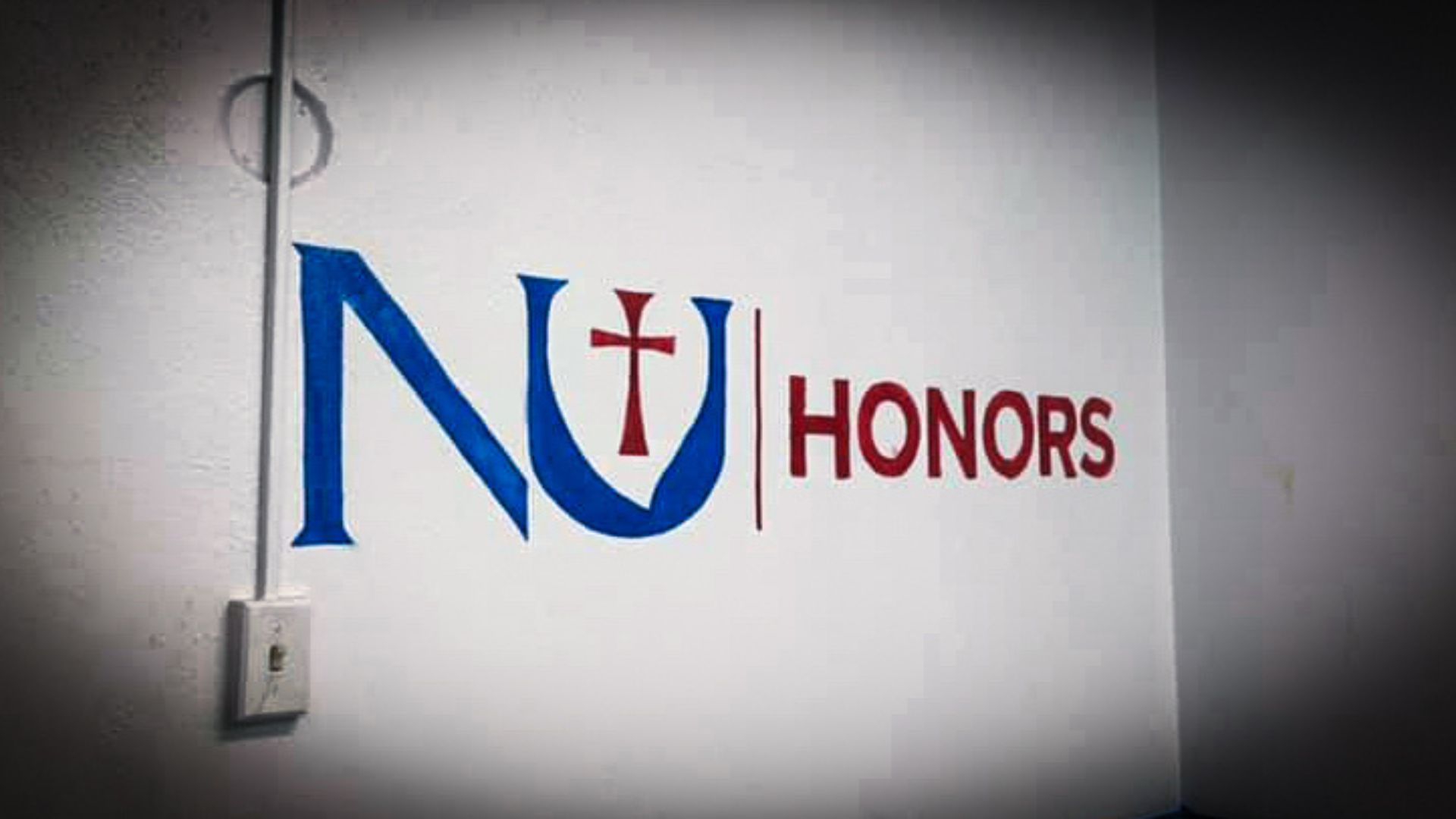 Honors Program Lounge shows "NU Honors" painted on the white wall