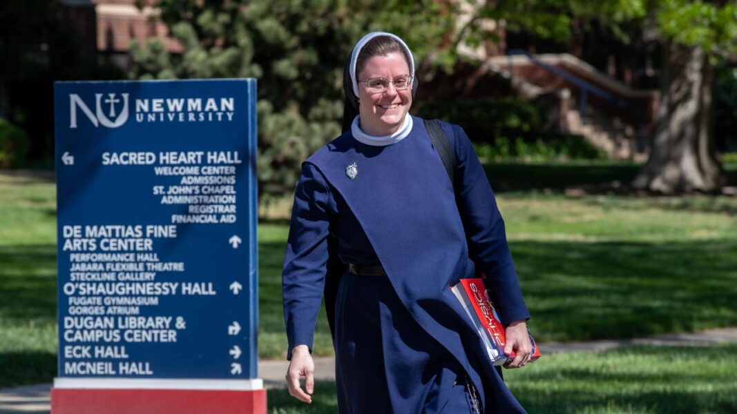 Swantek walks to class with a textbook in hand on the Newman campus.