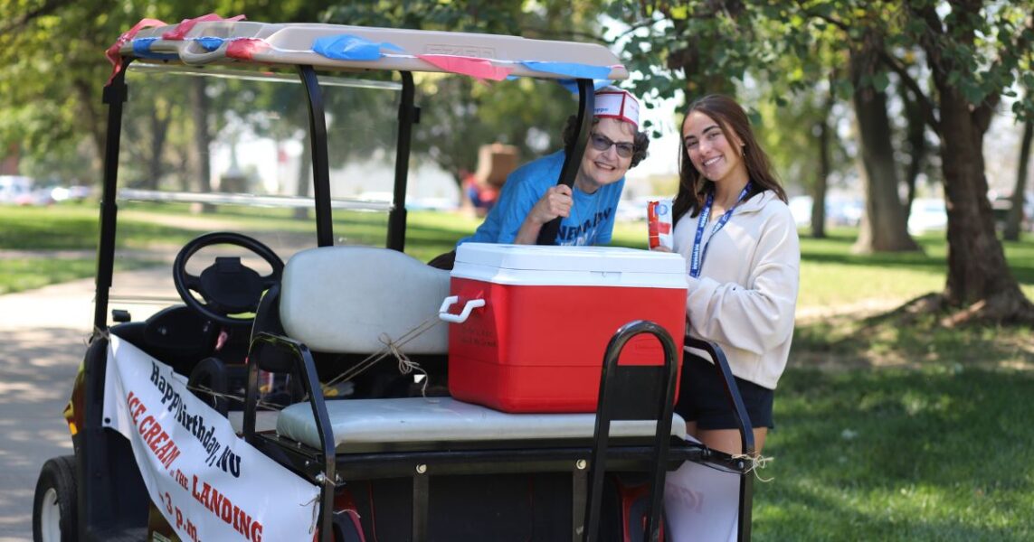 An ASC sister and a student pause for a smile next to the golf cart "ice cream truck."