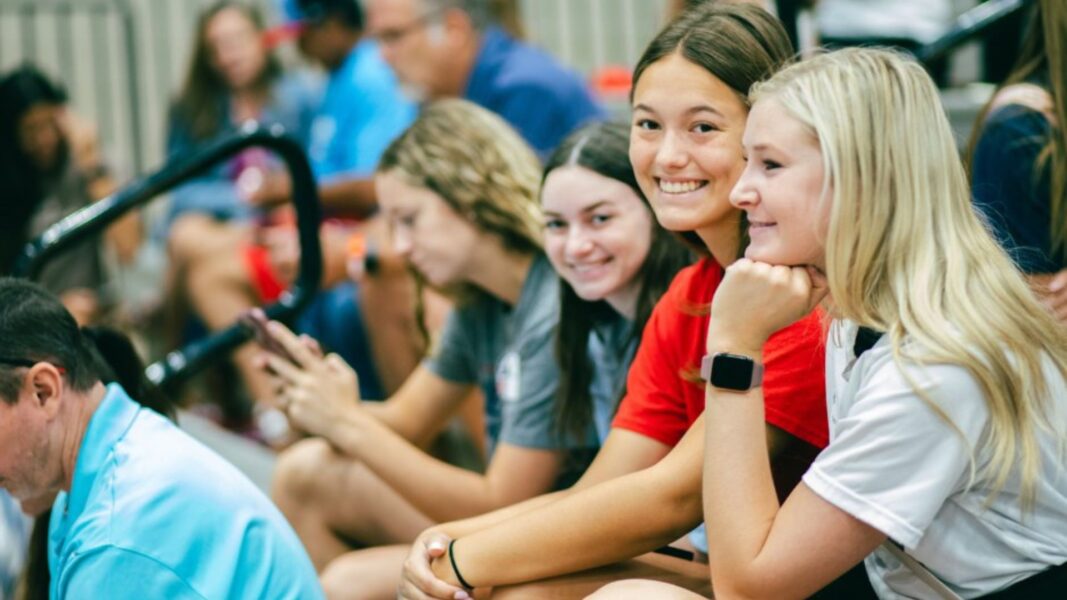 Students smile from the bleachers at Newman University