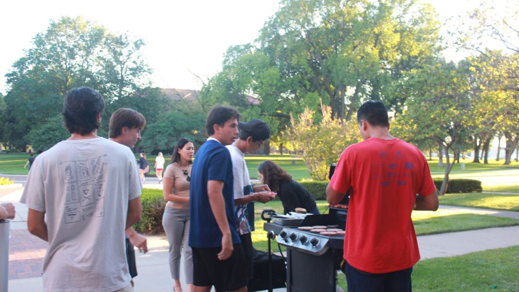 Students gather around the grill for dinner during the international student mixer.