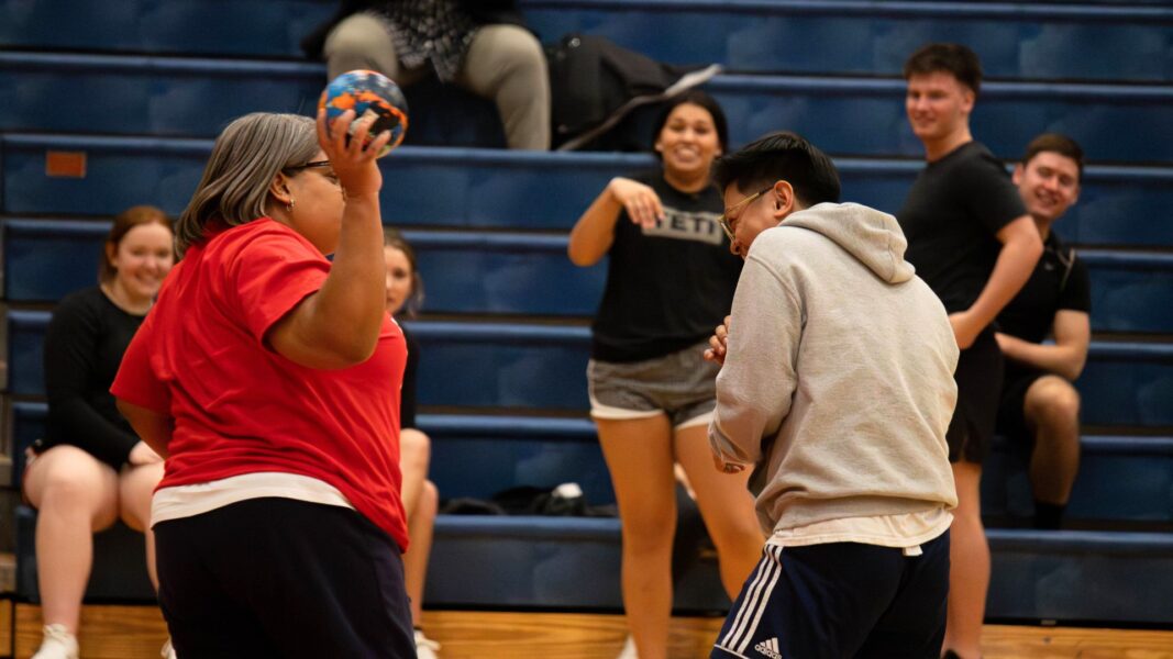 (Left to right) Staff member Candace Davis prepares to throw a dodgeball at graduate Florence Barles.  