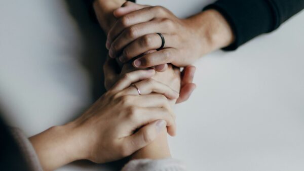 Two peoples' hands connect on a table in support.