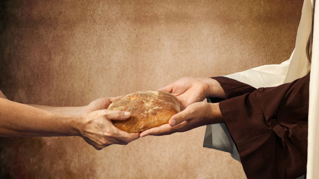 Two hands connect over an offering of bread