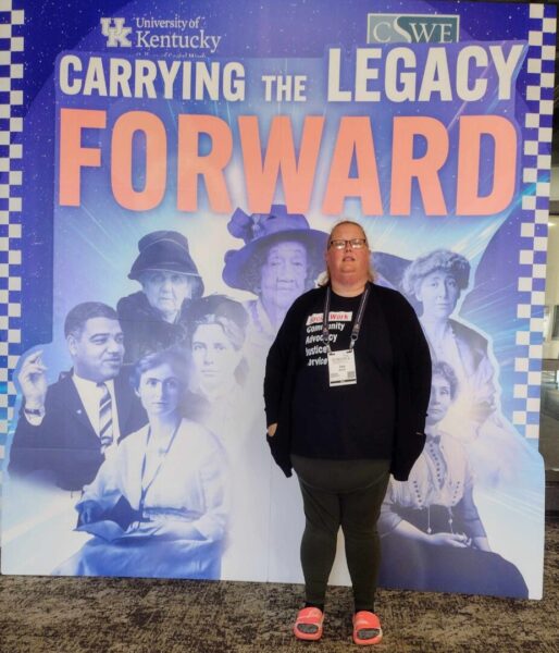 Garner stands in front of a sign that reads, "Carrying the Legacy Forward."