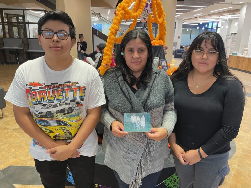 Perez-Lopez (right) stands with her mother and brother in front of the ofrenda.