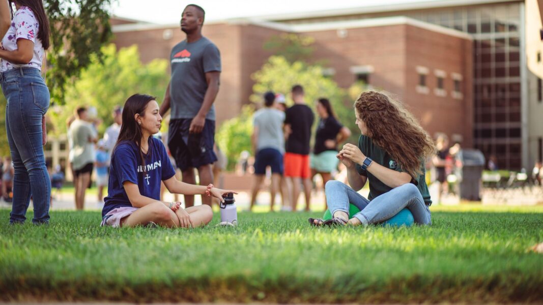 Students relax on the grass during a back to school event