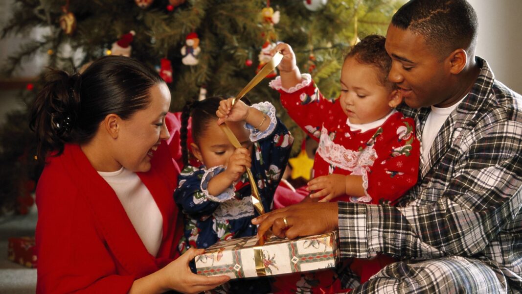 A couple helps their two children open Christmas presents