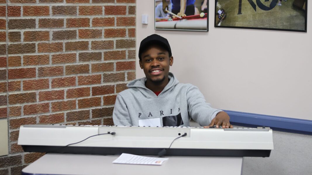 Lotsu-Morgan smiles from behind a piano keyboard during the 2024 Prayer Breakfast at Newman University.