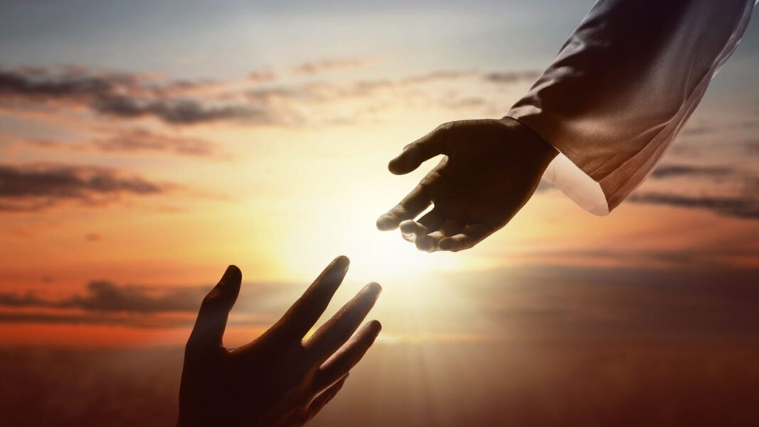 A person's hand reaches for Jesus'