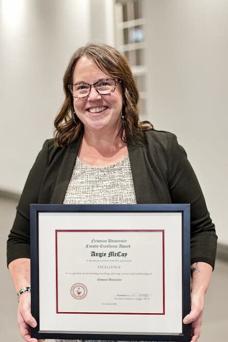 McCoy smiles as she holds up her excellence award