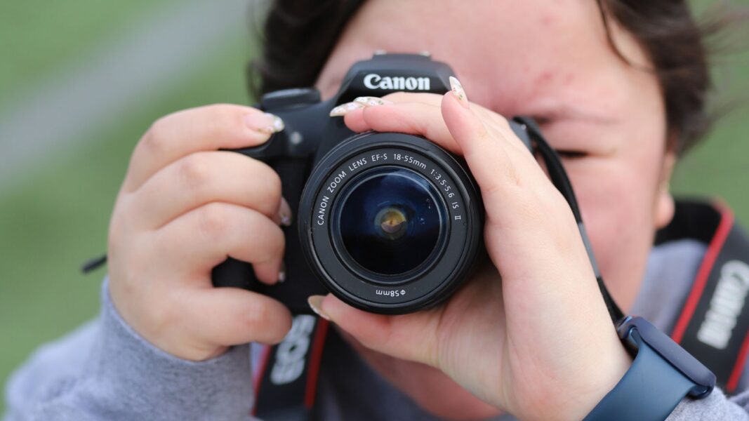 Andrea Fuentes holds up a camera during a Newman bubble soccer event