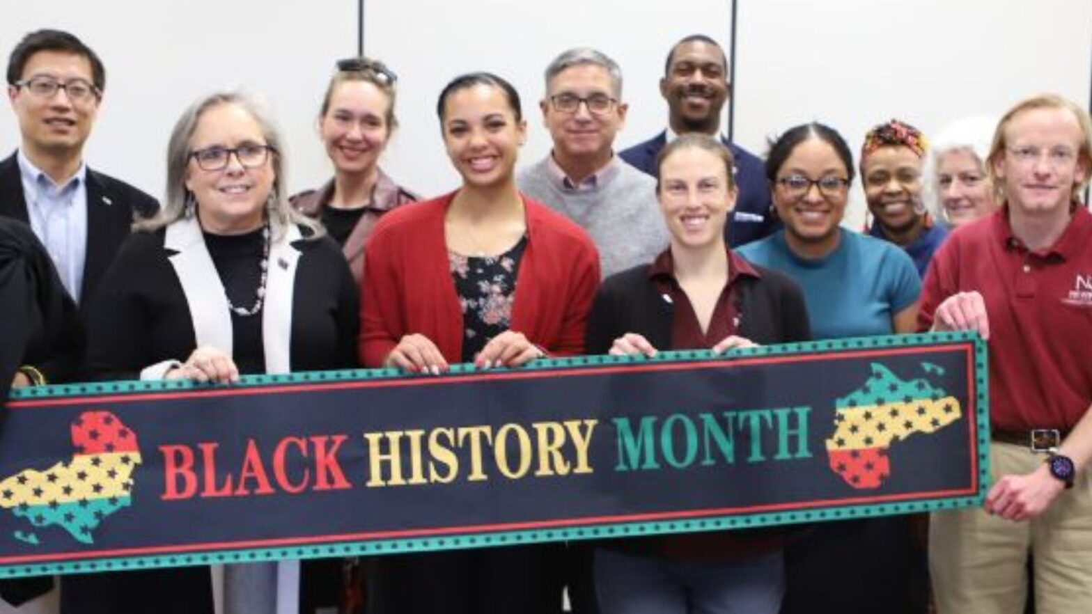 Students, faculty and staff hold up the "Black History Month" banner during the MLK Awards