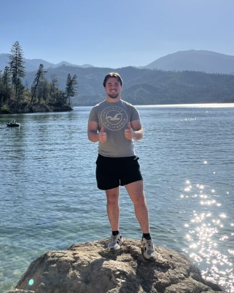 Masem stands on a rock overlooking the glistening blue water