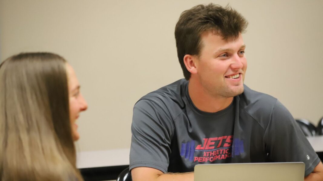 Students smile in one of Hane's communication courses at Newman University.