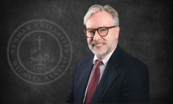 Michael "Mick" Cayless portrait photo with Newman University seal on dark background